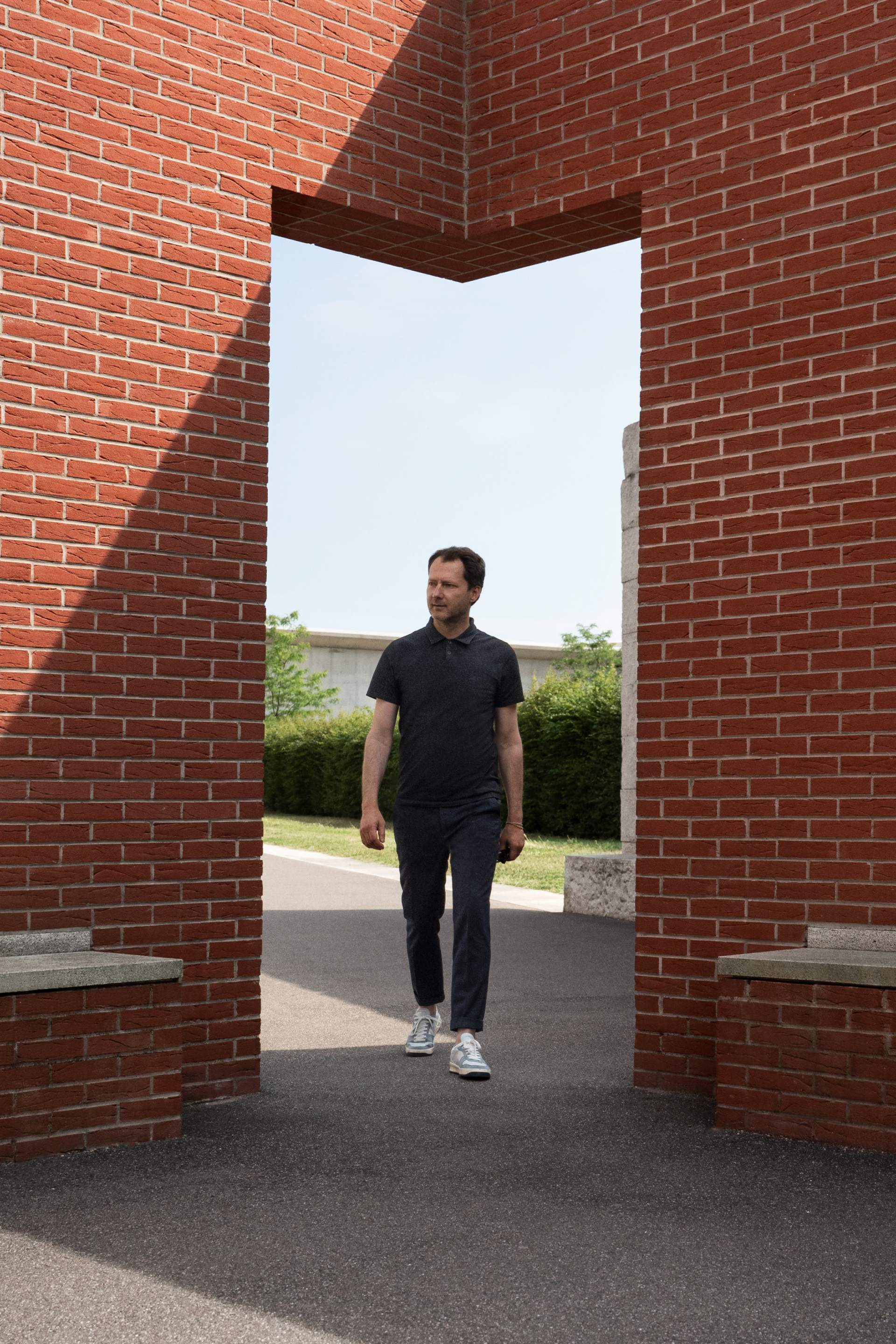 Mateo Kries walking through the entrance of the Álvaro Siza Promenade on the Vitra Campus.