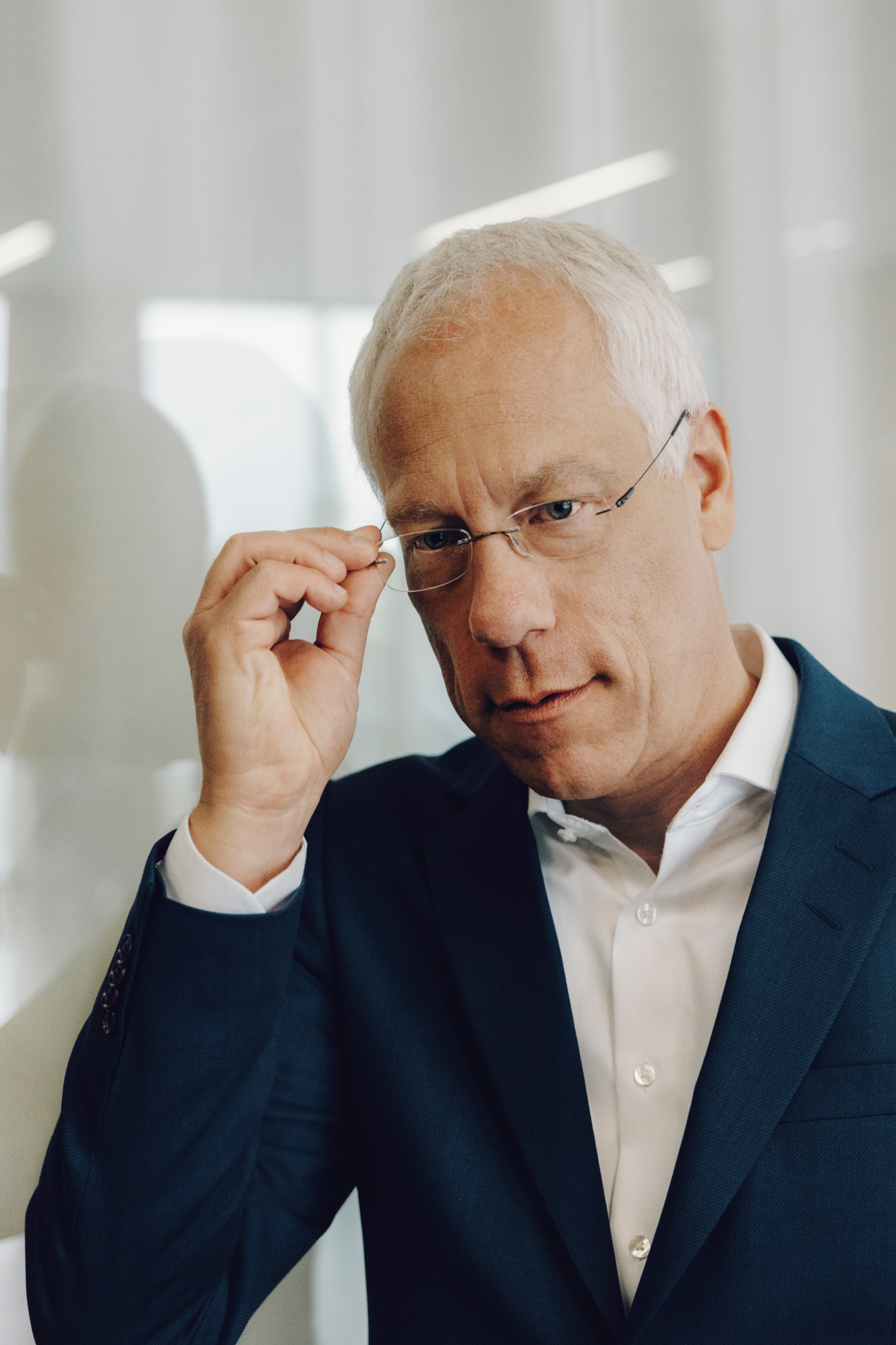 Peter Gladbach touching his glasses, looking into the camera.