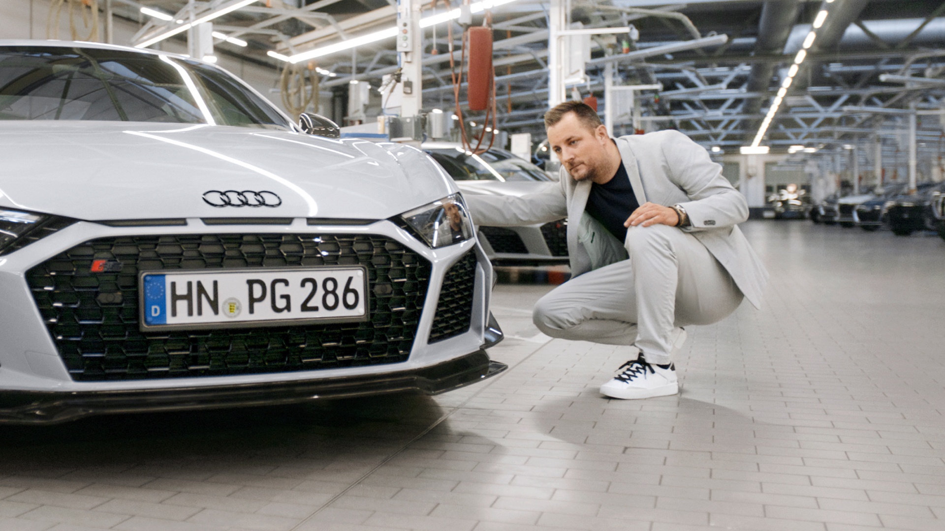 Sebastian Grams crouching next to an Audi R8 GT. 