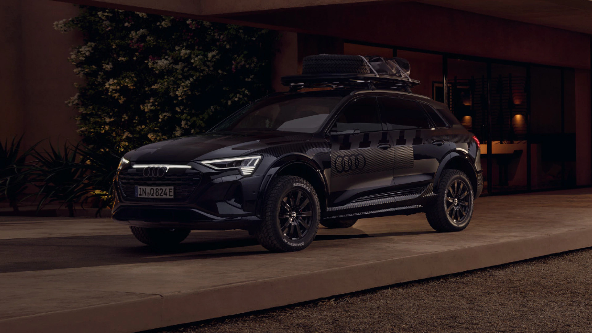 The Audi Q8 e-tron edition Dakar in front of a building. 