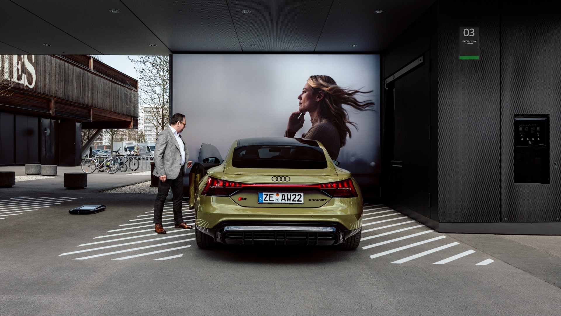 Helmuth Brants standing next to the Audi RS e-tron GT in front of a large screen.