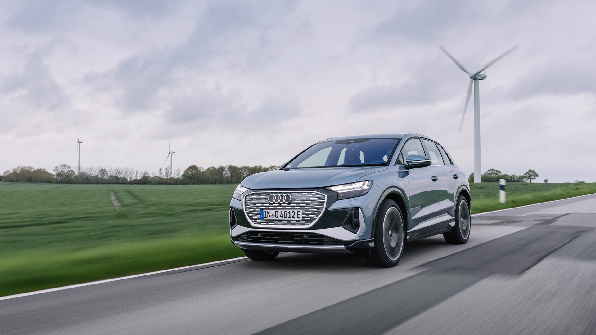 The Audi e-tron Sportback in front of wind turbines. 