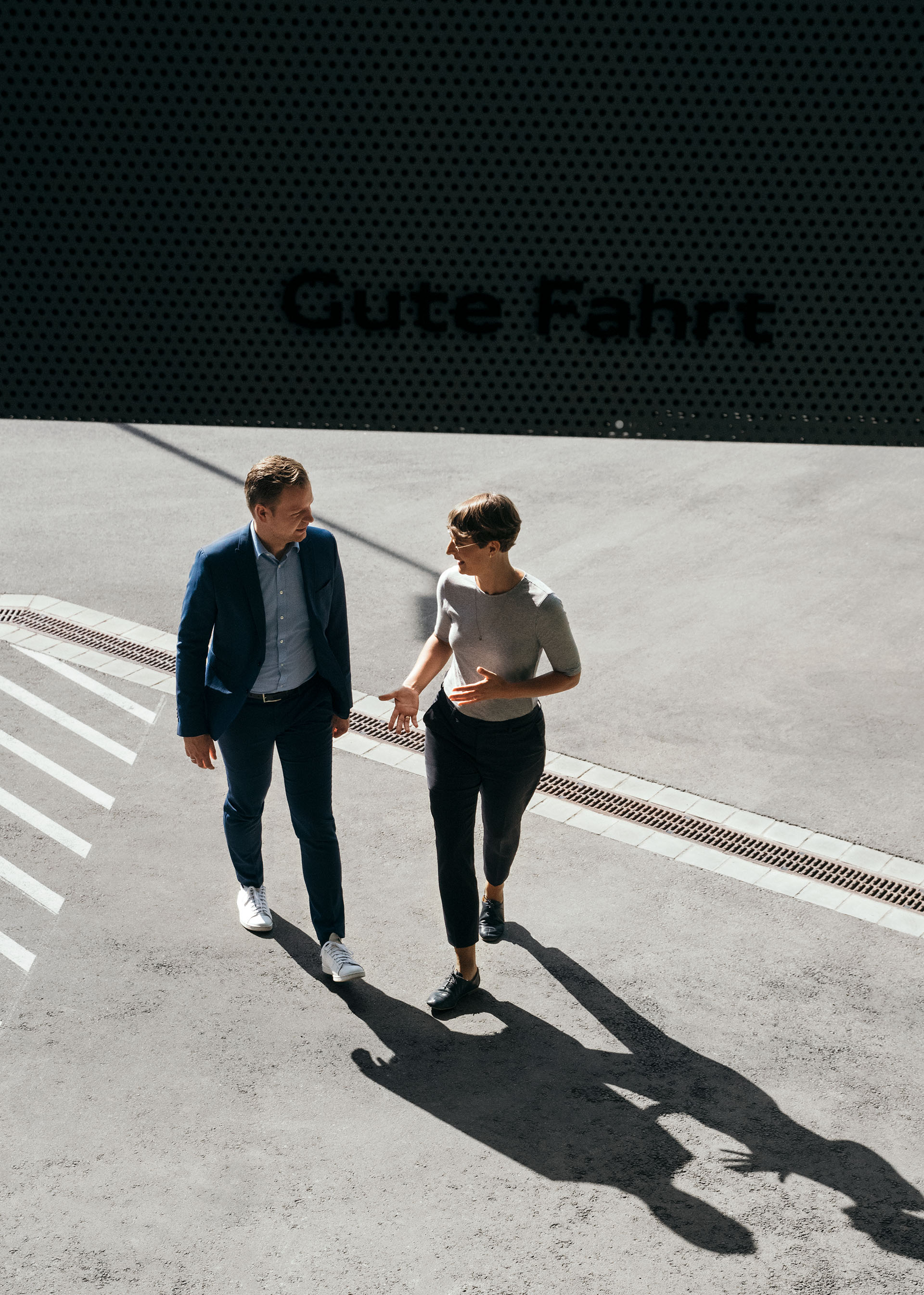 Sustainability experts Dr Johanna Klewitz and Malte Vömel move towards the entrance area of the lounge inside the Audi charging hub.