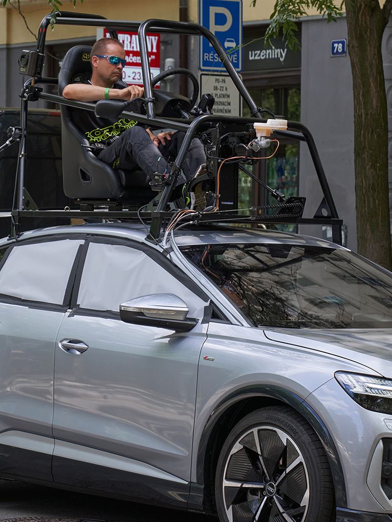 The Audi Q4 e-tron Sportback waits on set for the scene to be shot. A stunt driver can be seen sitting on the roof in the so-called pod car rig.