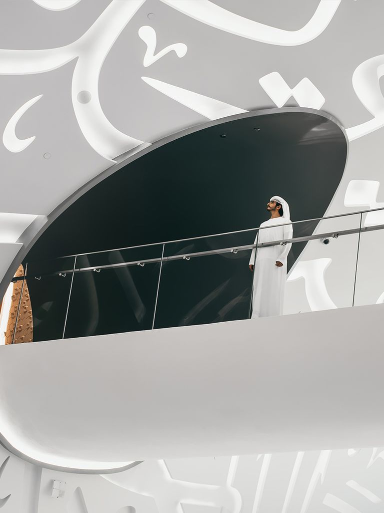 A man stands on a bridge inside the museum.