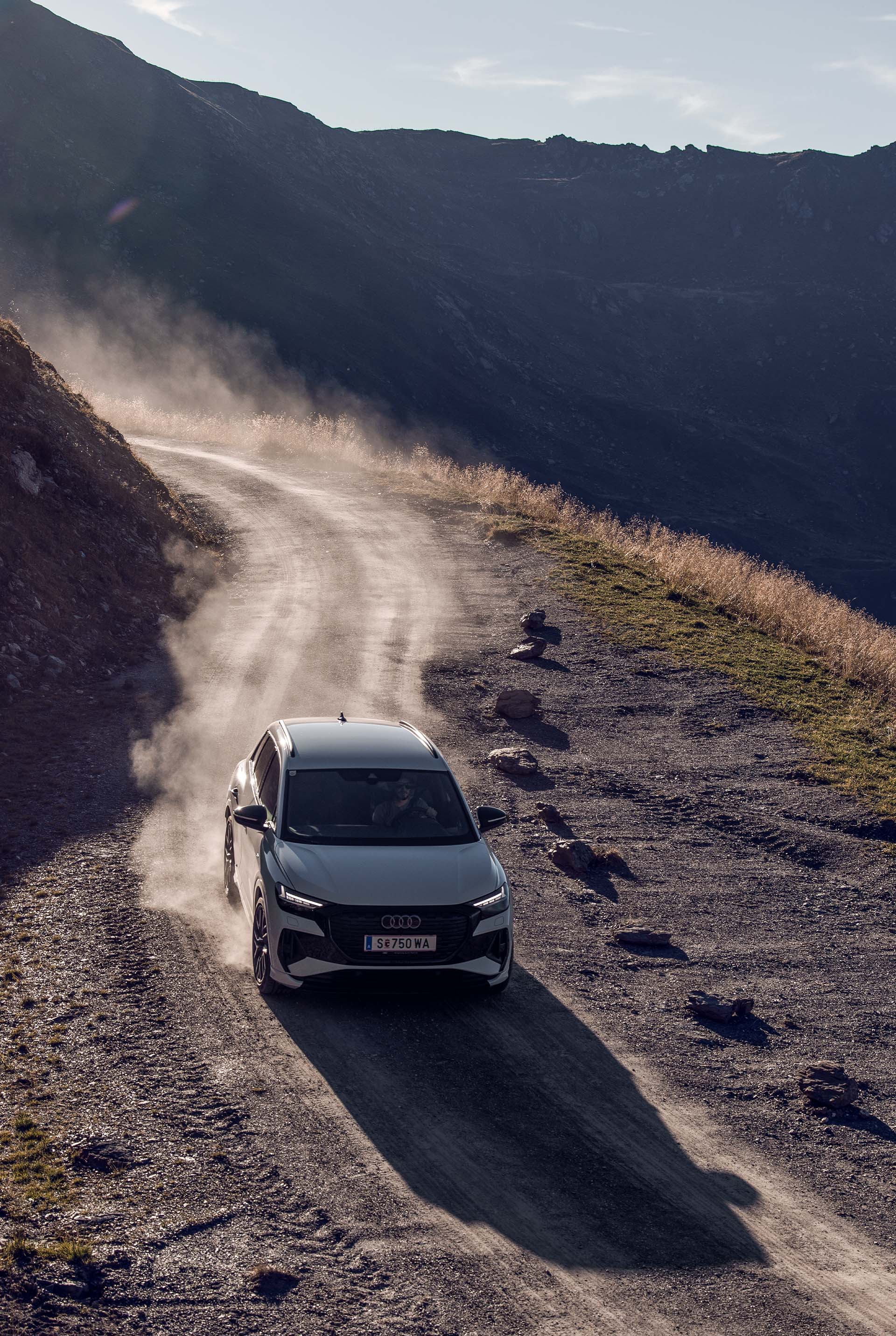 A white Audi Q4 e-tron drives down a mountain road.