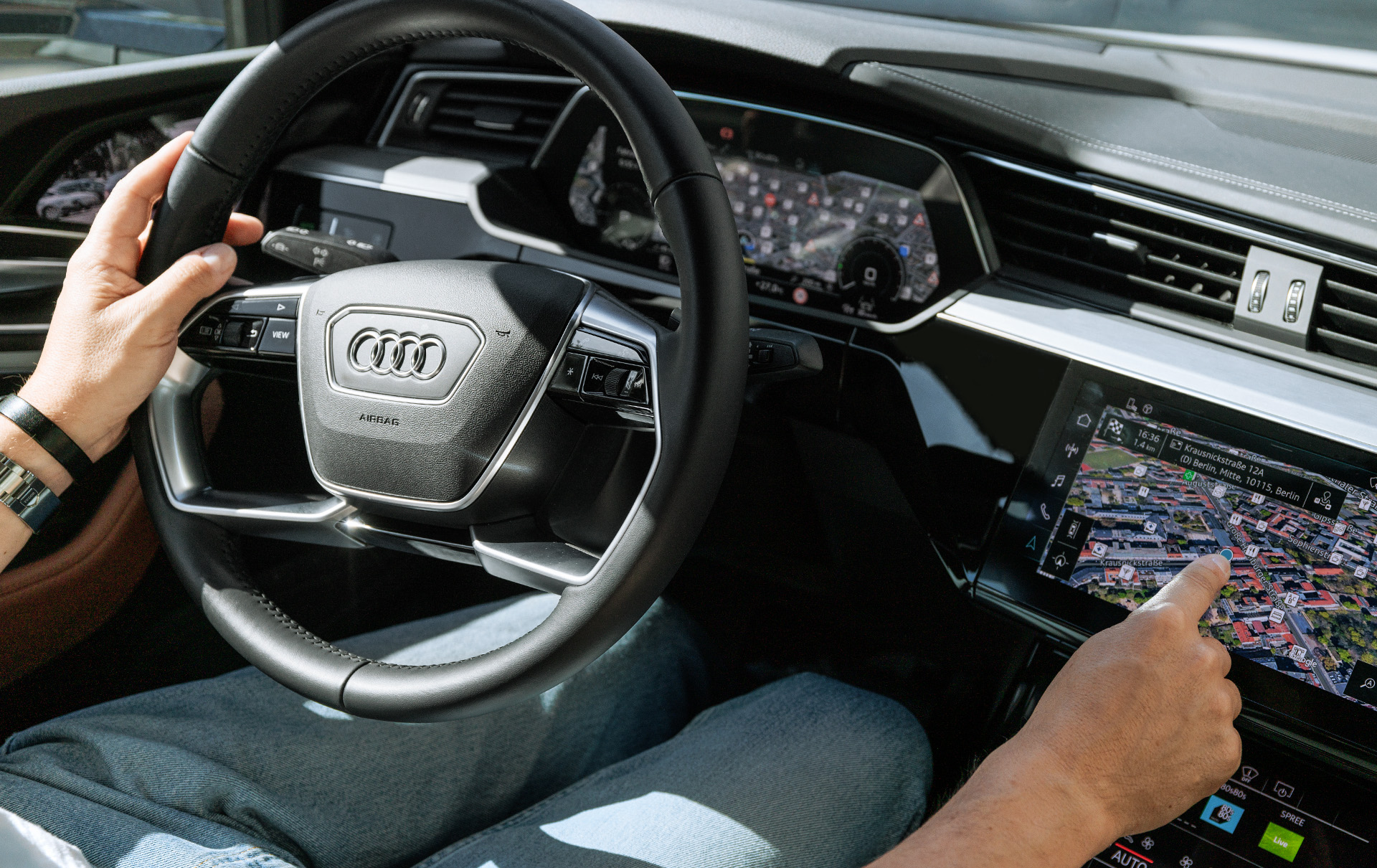 Marco Voigt sits at the steering wheel while the e-tron route planner shows him the available charging stations nearby.