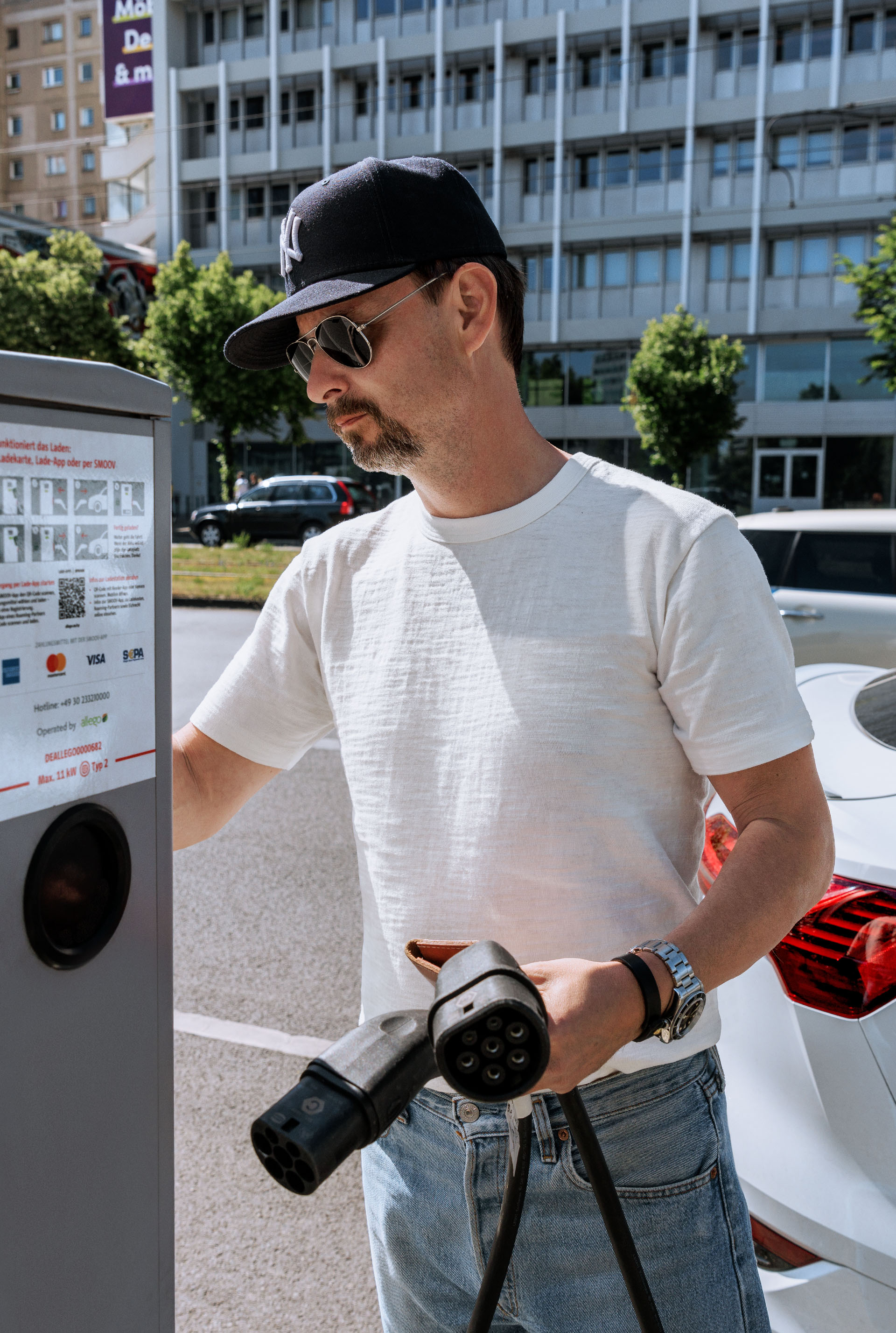 A close-up of Marco Voigt’s hand as he plugs the charging cable into the electric vehicle. 