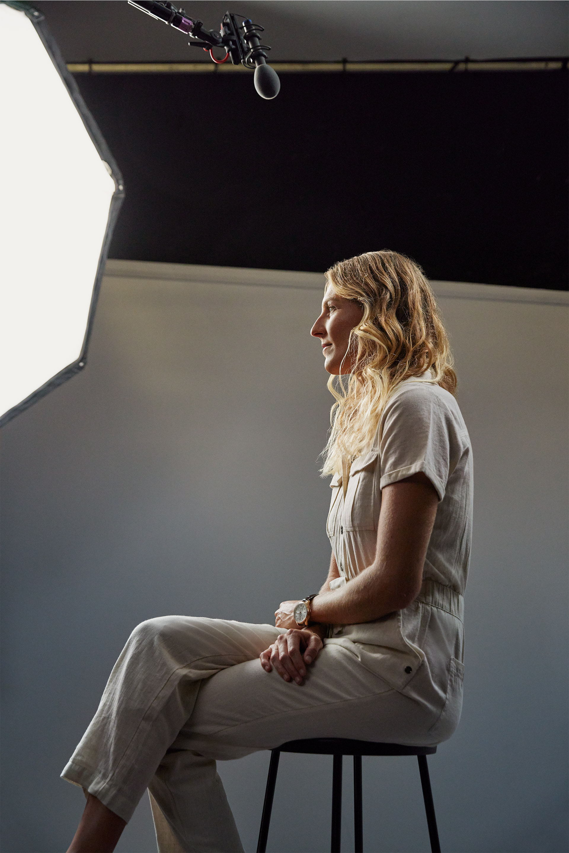 Stephanie Gilmore on set, sitting on a bar stool. 