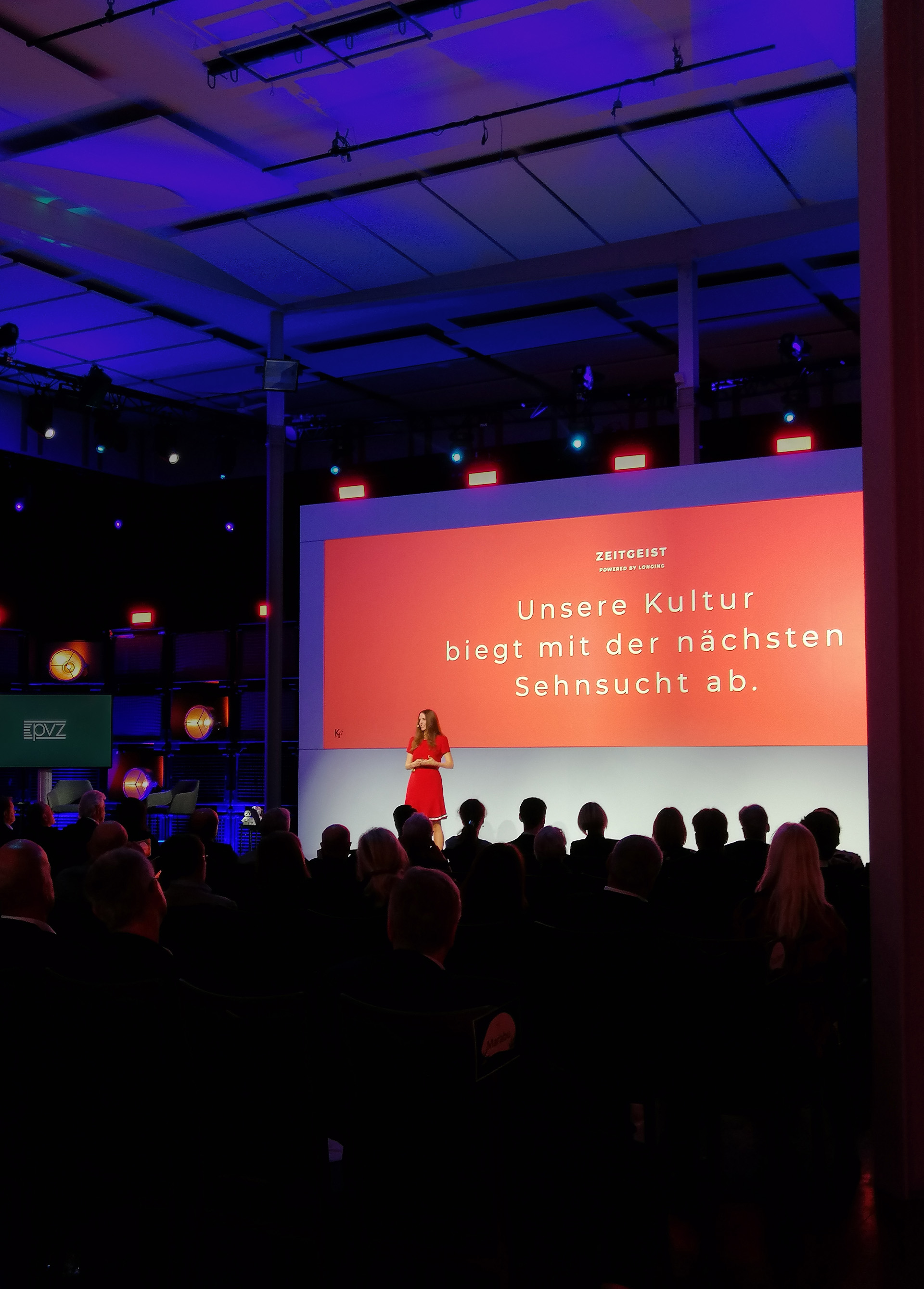 View of the stage from the audience, where Kirstine Fratz is giving a presentation.