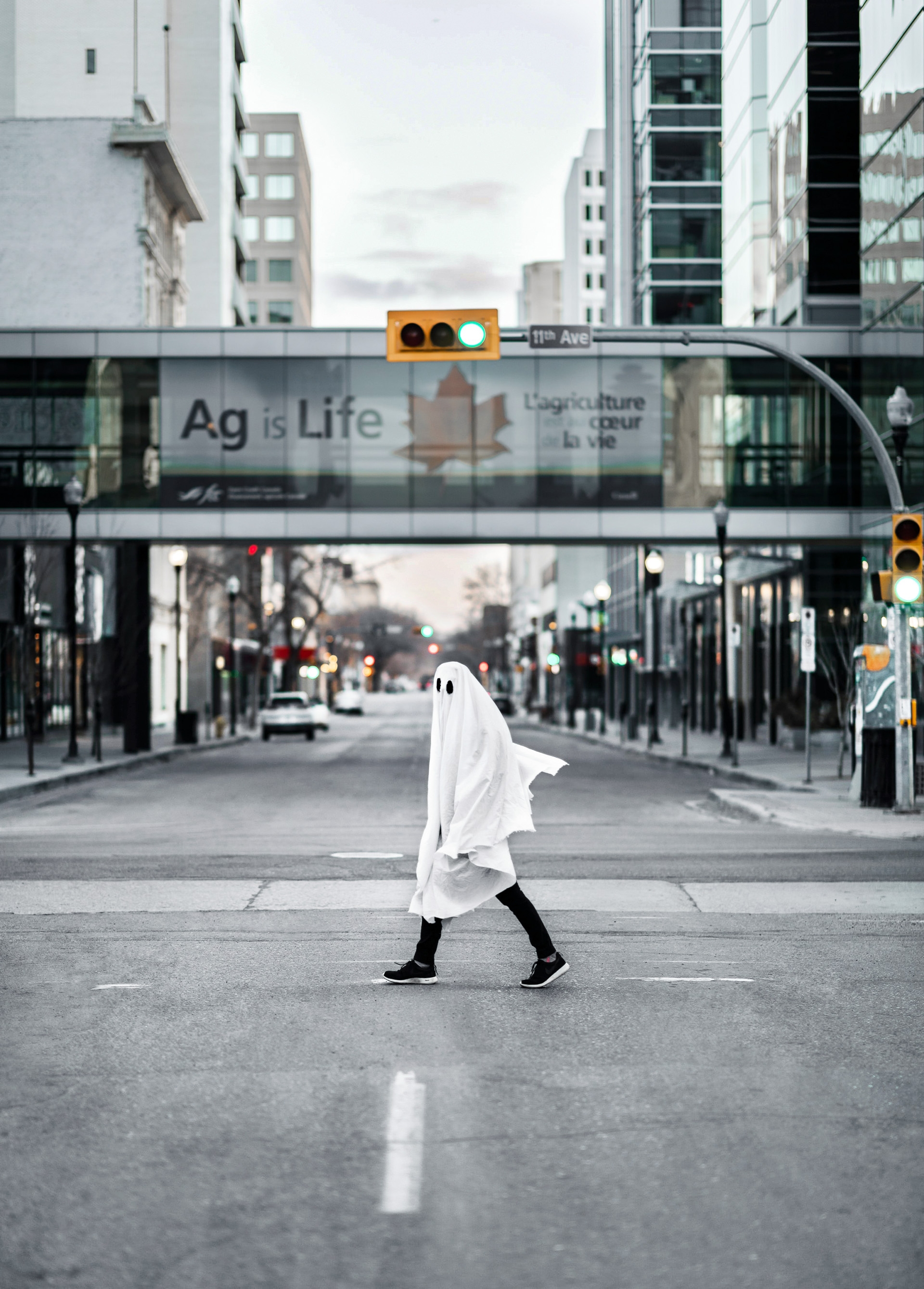 A person dressed as a ghost walks on the street.